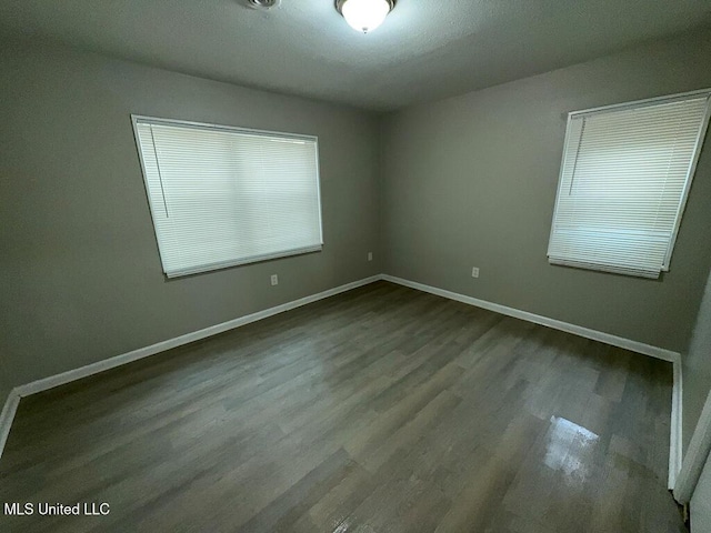 spare room with baseboards and wood finished floors