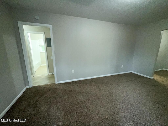 spare room with baseboards and dark carpet