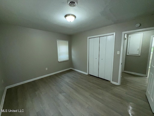 unfurnished bedroom with baseboards, a closet, visible vents, and wood finished floors