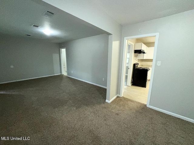 spare room featuring dark colored carpet, visible vents, and baseboards