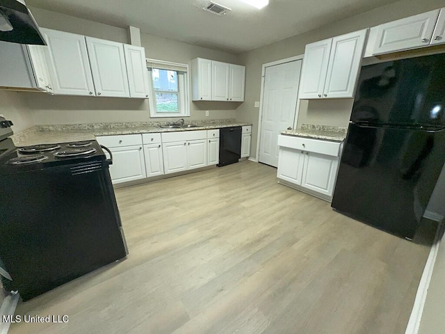 kitchen with black appliances, range hood, visible vents, and light wood finished floors