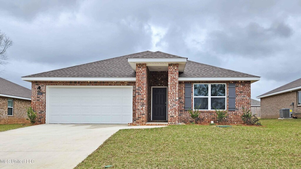 view of front of home with cooling unit, a garage, and a front yard