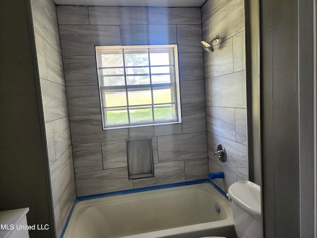 bathroom featuring toilet and tiled shower / bath