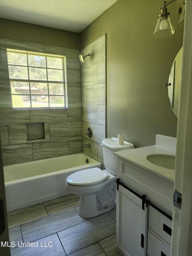 full bathroom featuring vanity, toilet, a textured ceiling, and tiled shower / bath