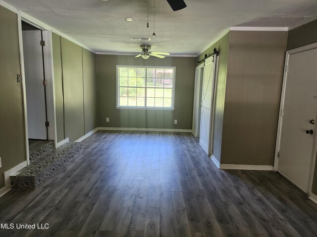 interior space featuring ornamental molding, dark wood-type flooring, a barn door, and ceiling fan