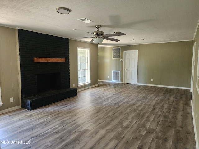 unfurnished living room featuring hardwood / wood-style floors, crown molding, a fireplace, and ceiling fan