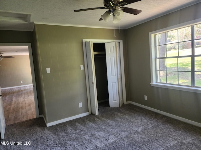 unfurnished bedroom featuring carpet, ceiling fan, a textured ceiling, a closet, and crown molding