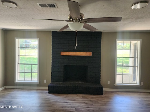 unfurnished living room featuring hardwood / wood-style floors, a fireplace, a textured ceiling, and ceiling fan