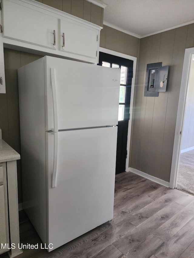 kitchen with white cabinetry, light hardwood / wood-style floors, ornamental molding, electric panel, and white refrigerator