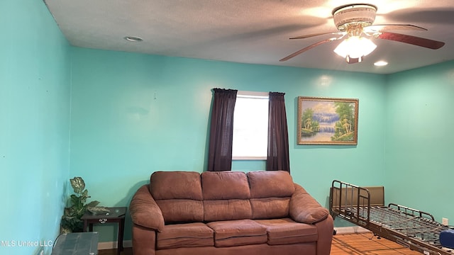 living room featuring ceiling fan, light hardwood / wood-style flooring, and a textured ceiling