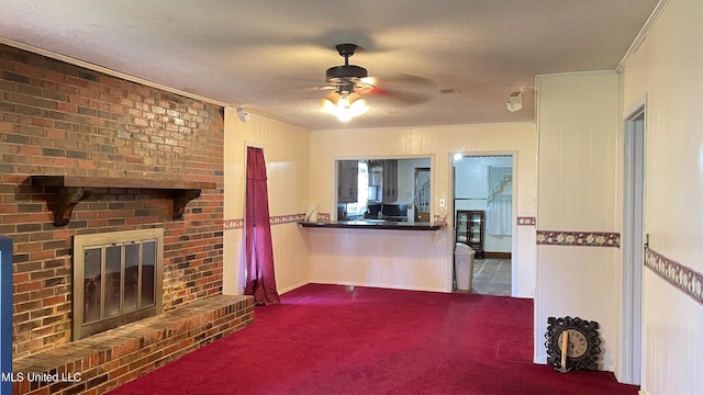 unfurnished living room with carpet flooring, a textured ceiling, ceiling fan, crown molding, and a fireplace