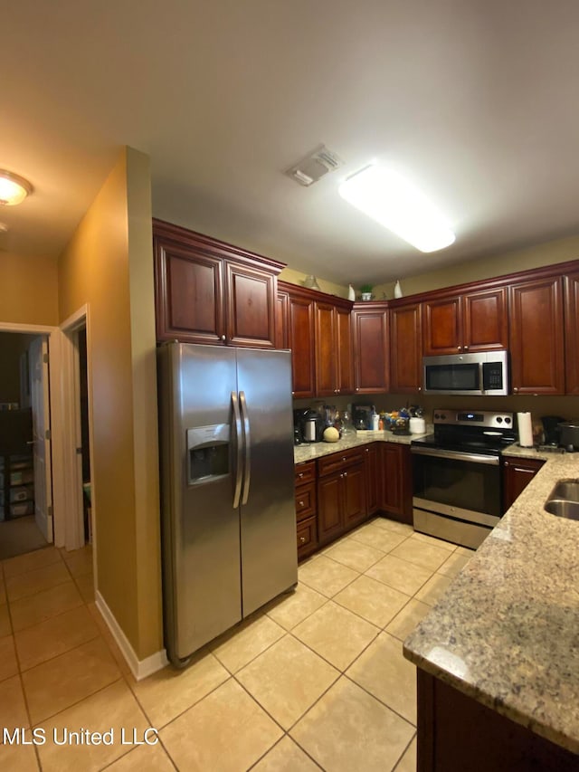 kitchen featuring light stone counters, appliances with stainless steel finishes, and light tile patterned floors