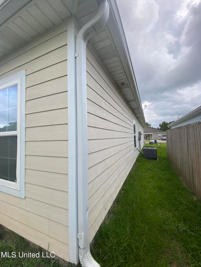 view of side of property featuring central air condition unit and a lawn