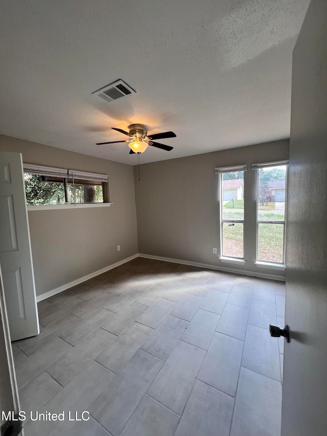 spare room featuring a wealth of natural light, ceiling fan, and a textured ceiling