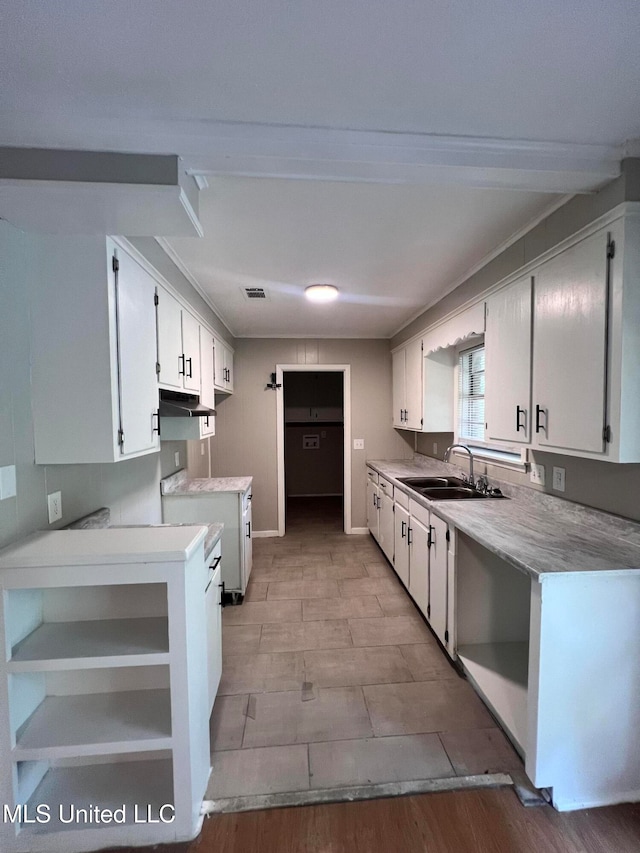 kitchen with stove, white cabinetry, sink, and light wood-type flooring