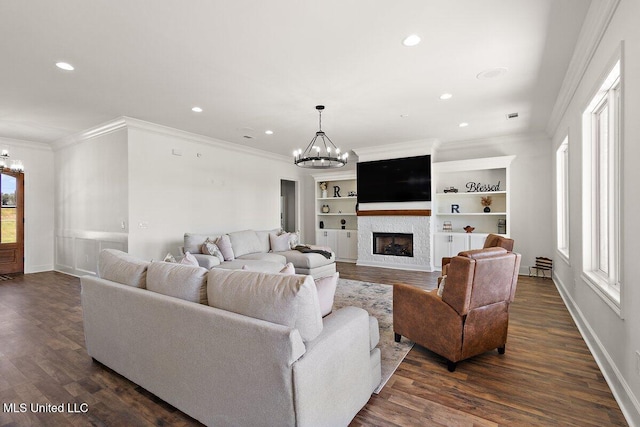 living room featuring dark wood-type flooring, crown molding, a notable chandelier, and a wealth of natural light