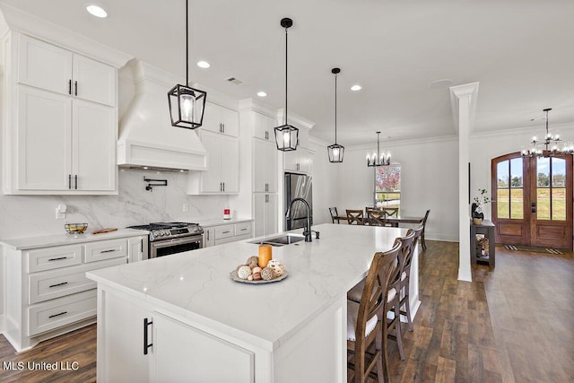 kitchen featuring a large island with sink, sink, white cabinets, and stainless steel appliances