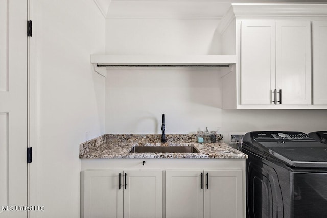 washroom with sink, washing machine and dryer, and cabinets