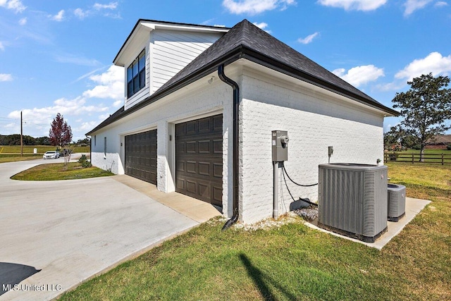 view of side of home featuring cooling unit, a garage, and a lawn