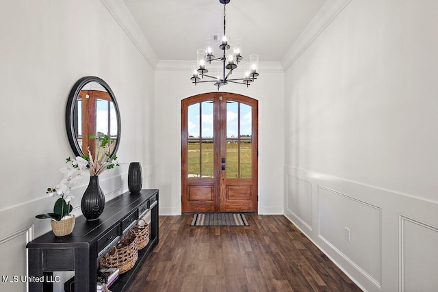 foyer entrance with ornamental molding, a notable chandelier, french doors, and dark hardwood / wood-style flooring