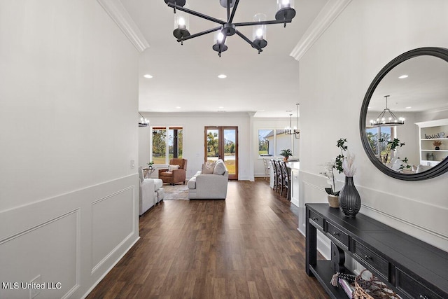 hall featuring dark wood-type flooring, ornamental molding, an inviting chandelier, and french doors