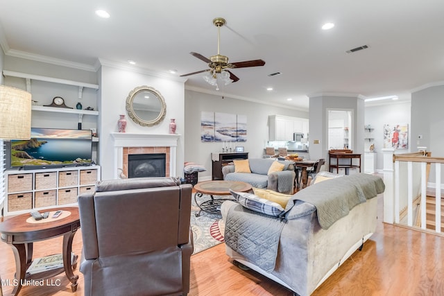 living room with ornamental molding, a fireplace, and light wood-type flooring