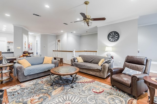 living room featuring light hardwood / wood-style flooring, ornamental molding, and ceiling fan