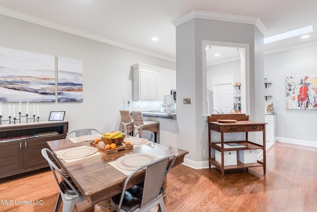 dining space with ornamental molding and light hardwood / wood-style flooring