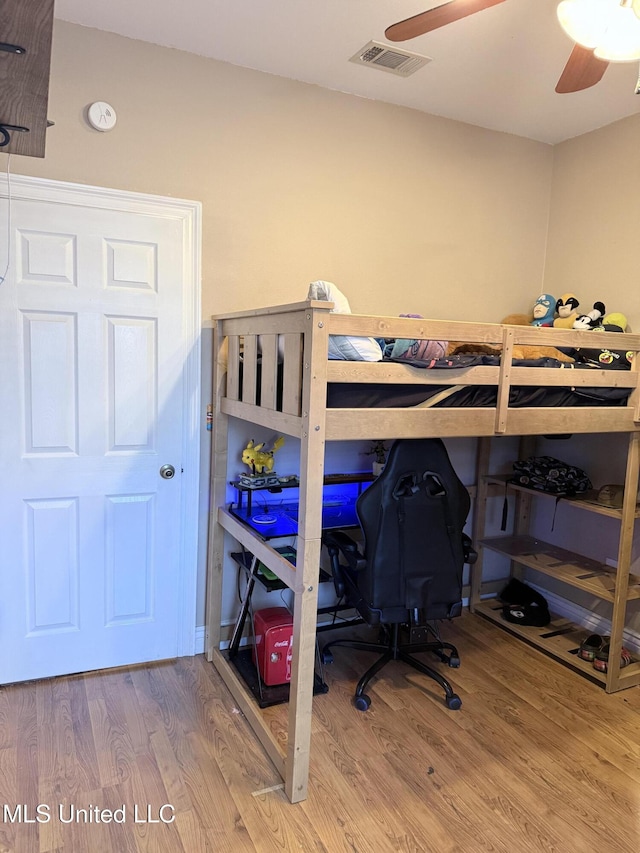 bedroom with a ceiling fan, visible vents, and wood finished floors