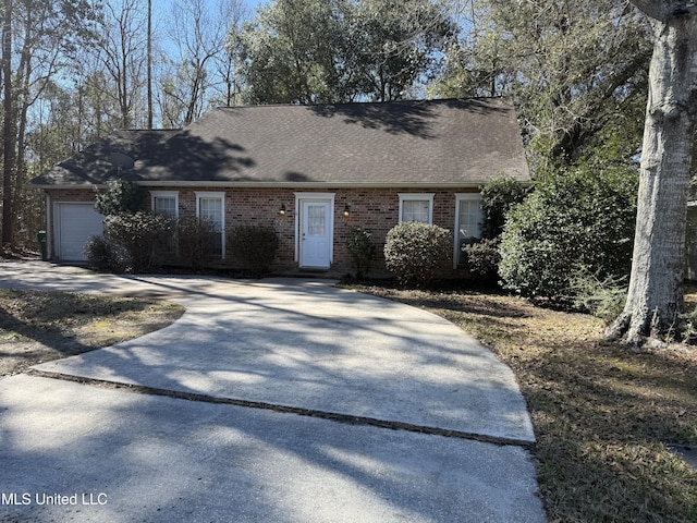 view of front facade with driveway, brick siding, an attached garage, and a shingled roof