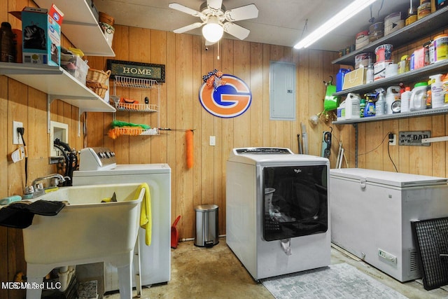 washroom featuring wooden walls, ceiling fan, washing machine and dryer, electric panel, and laundry area