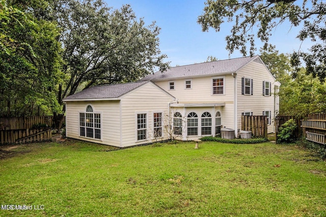 rear view of property featuring cooling unit, a lawn, and a fenced backyard