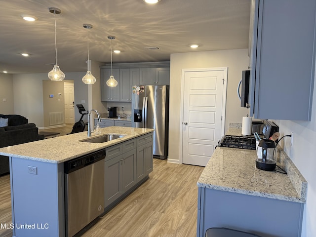 kitchen featuring sink, hanging light fixtures, light hardwood / wood-style flooring, an island with sink, and stainless steel appliances