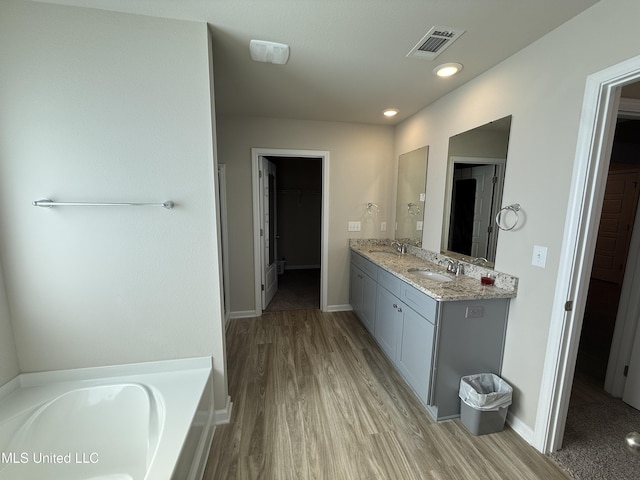 bathroom with hardwood / wood-style flooring, vanity, and a bathtub