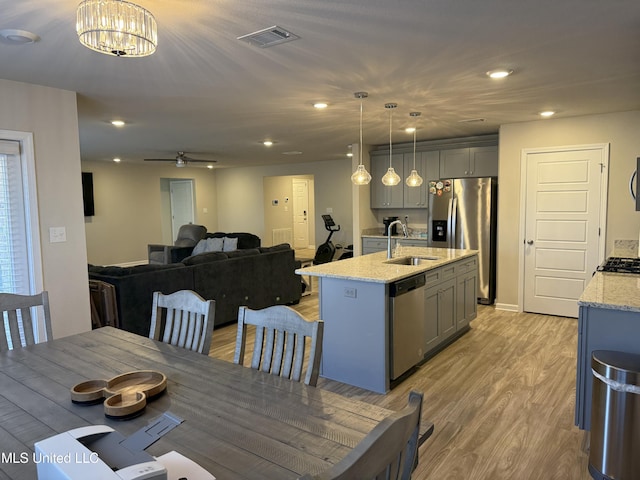 dining area featuring ceiling fan with notable chandelier, light hardwood / wood-style floors, and sink