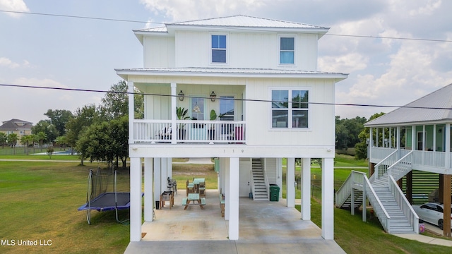 rear view of house featuring a patio, ceiling fan, a lawn, and a trampoline