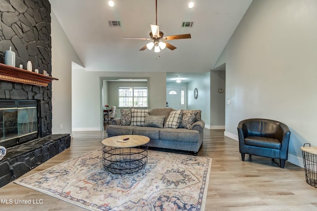 living room with ceiling fan, high vaulted ceiling, a fireplace, and light hardwood / wood-style floors