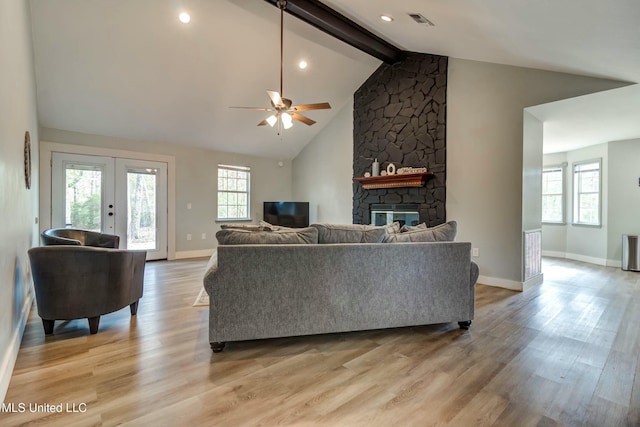 living room featuring ceiling fan, lofted ceiling with beams, a fireplace, and light hardwood / wood-style floors