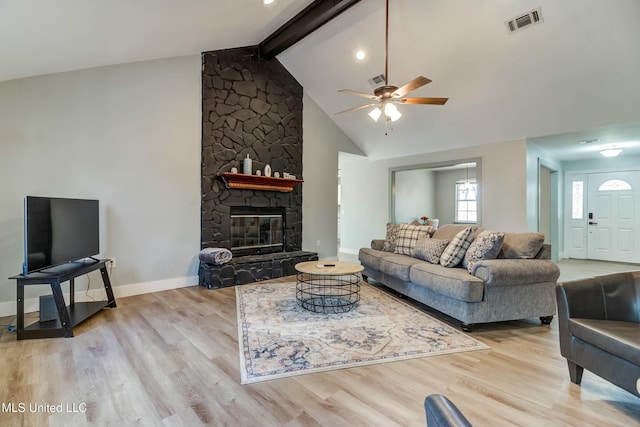 living room with ceiling fan, light wood-type flooring, a fireplace, high vaulted ceiling, and beamed ceiling