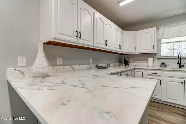 kitchen featuring light stone countertops, sink, white cabinets, and light hardwood / wood-style floors