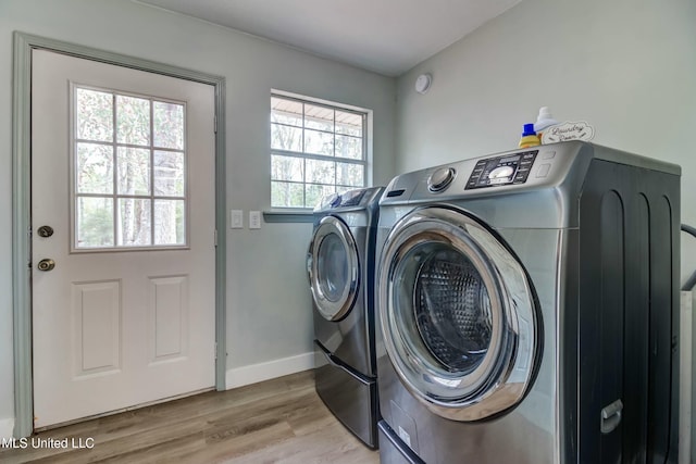 laundry area with washer and dryer, a wealth of natural light, and light wood-type flooring