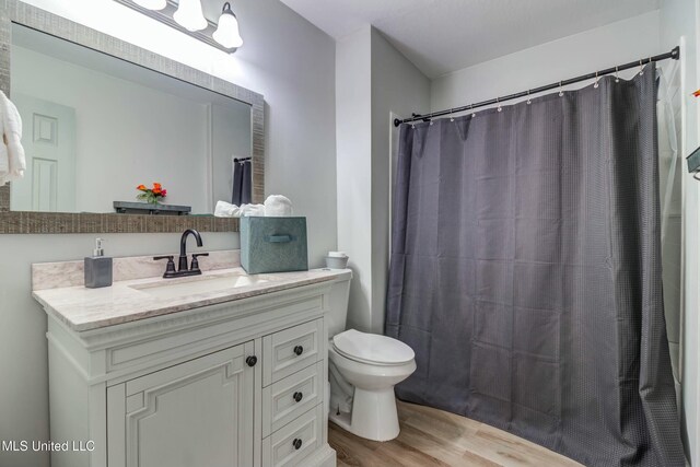 bathroom with toilet, vanity, a shower with shower curtain, and hardwood / wood-style floors