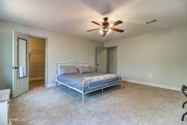 carpeted bedroom with a spacious closet, ceiling fan, and a closet