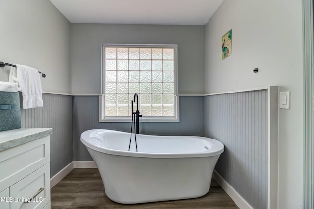 bathroom featuring vanity, a washtub, and hardwood / wood-style floors