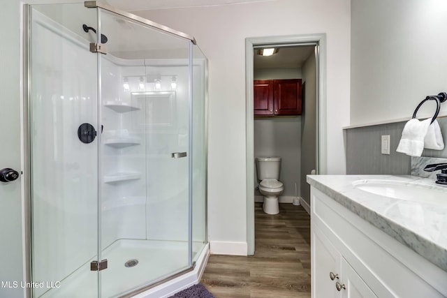 bathroom featuring hardwood / wood-style flooring, toilet, walk in shower, and vanity