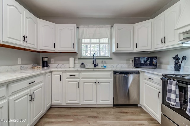 kitchen with light stone countertops, white cabinets, appliances with stainless steel finishes, sink, and light hardwood / wood-style flooring