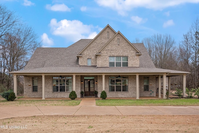 view of front of property featuring covered porch, brick siding, roof with shingles, and a front yard