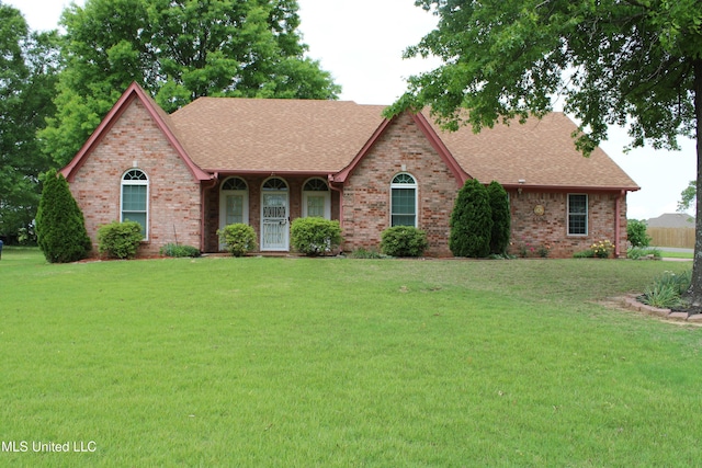 view of front facade featuring brick siding, a shingled roof, and a front yard
