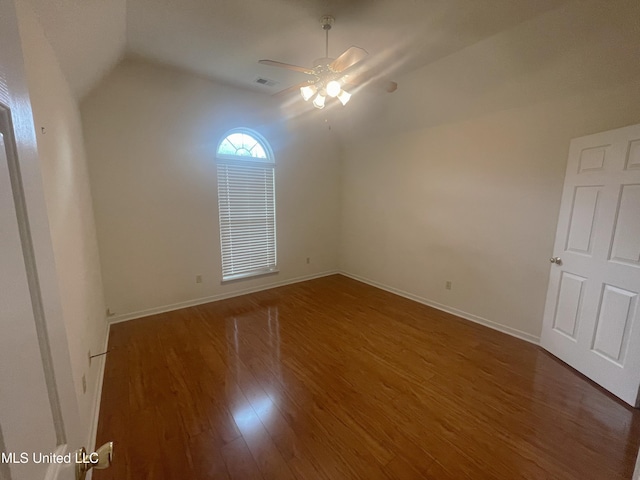 spare room featuring ceiling fan, visible vents, vaulted ceiling, wood finished floors, and baseboards