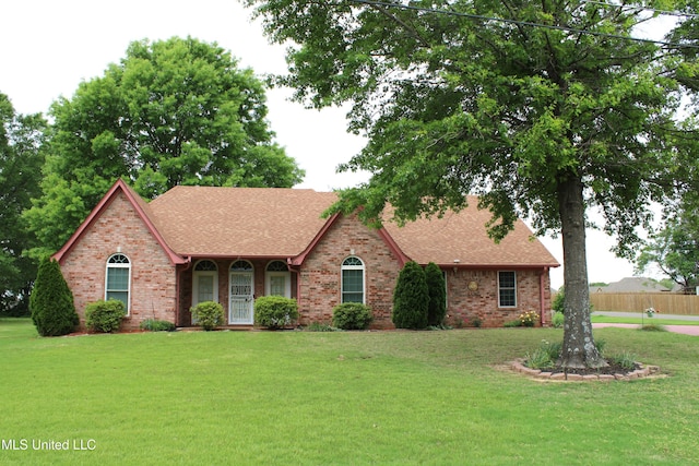 view of front of property with brick siding, a shingled roof, and a front lawn